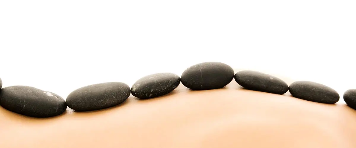 Warme Basaltsteine liegen bei einer Hot Stone Massage auf dem Rücken